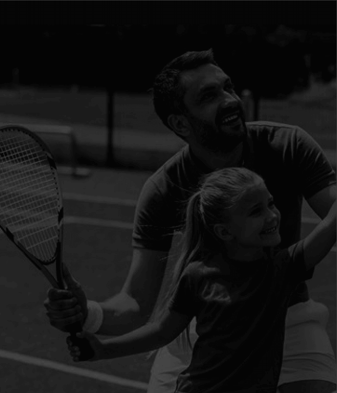 A father teaching his daughter how to play tennis